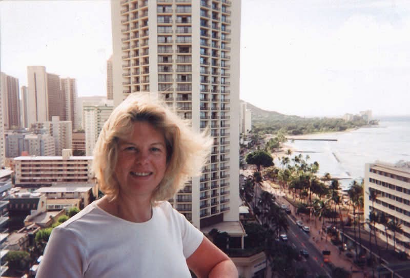 Pretty blonde woman standing on a balcony overlooking Waikiki in Honolulu Hawaii